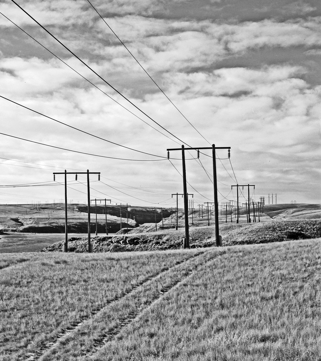 Overview view of Morony-tp-Rainbow Line (right) about one-fourth mile northeast of Rainbow Dam. Ryan-to-Rainbow Lines 1 and 2 at center, Cochrane-to-Rainbow Line at left and Rainbow Dam in background right of center. View to southwest - Morony Hydroelectric Facility, Morony-to-Rainbow 100 kV Transmission Line, West bank of the Missouri River, Great Falls, Cascade County, MT